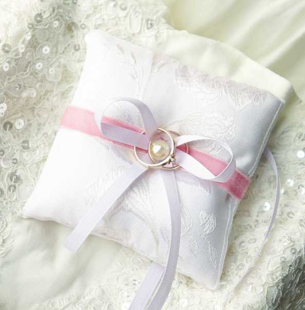 В последнее время стало очень популярно использовать на свадьбе различные подушечки для обручальных колец. Это удобно, красиво и безусловно добавляет торжеству эксклюзивности. Если вышить на